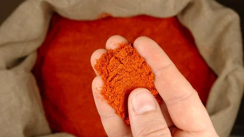 TOP VIEW: Human hand takes a pinch of red pepper powder from a sac Stock Footage 90442464