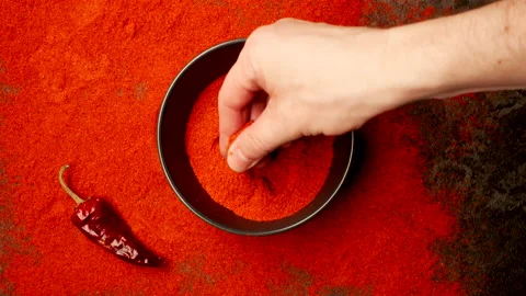 TOP VIEW: Human hand takes a pinch from a dish with red pepper powder Stock Footage 150418439