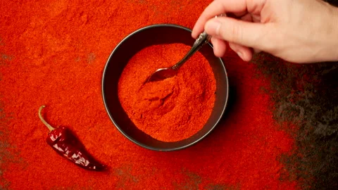 TOP VIEW: Human hand takes red pepper powder by a spoon from a dish Vídeo Stock 150418599