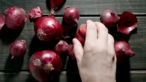 TOP VIEW: Human hand takes a red onion bulb on a wooden dark table Stock Footage 202066073