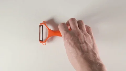 TOP VIEW: Human hands puts a peeler on a white table Vídeos de archivo 74730069