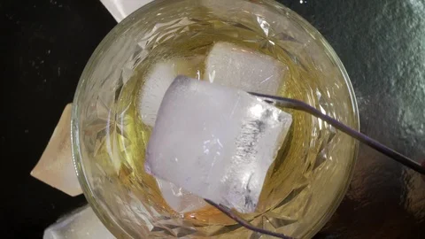 Top  VIew of  ice cube falls and melts in a glass of whiskey. Golden Whiskey Stock Footage 124468149