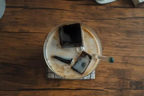 Top View of Iced Coffee with Coffee Ice Cubes in Glass on Wooden Table Stock Photos
