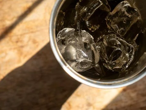 Top view of iced drink in stainless steel cup on rustic wooden table with d.. Stock Photos