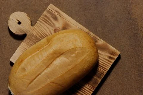 Top view image of a loaf of bread on a kitchen board. Stock Photos