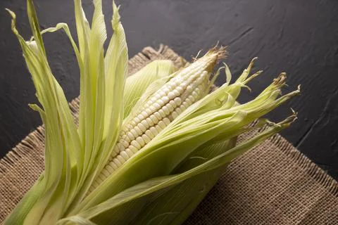 Top View Image of raw white corn on the cob on black rustic surface. copy spa Stock Photos