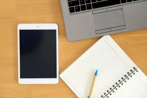 Top view image of tablet device, paper note over wooden background Stock Photos