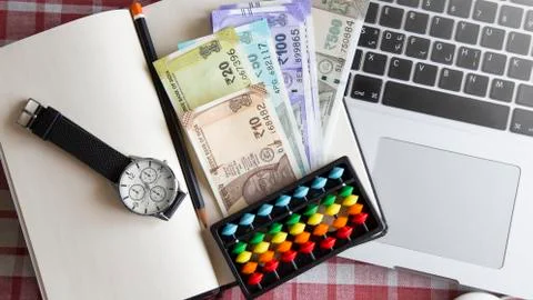 Top view Indian currency notes, abacus board, watch and note book on the laptop. Stock Photos