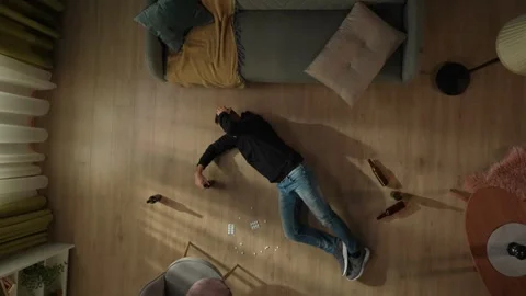 Top view of an intoxicated man with a bottle of beer lying on the floor among Stock Footage 255208308