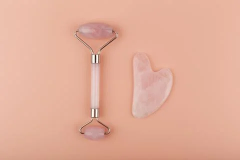 Top view of jade roller and heart shaped massager made of pink quartz on beige Stock Photos