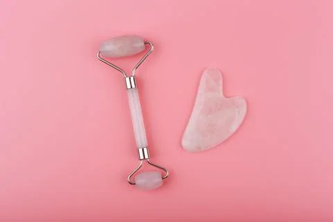 Top view of jade roller and heart shaped massager made of pink quartz on pink Stock Photos