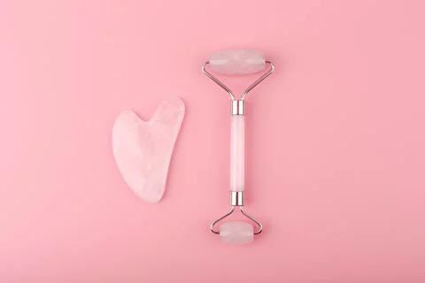 Top view of jade roller and heart shaped massager made of pink quartz on pink Stock Photos