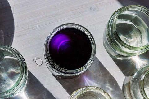 Top view of a jar filled with deep purple food dye solution surrounded by c.. Stock Photos