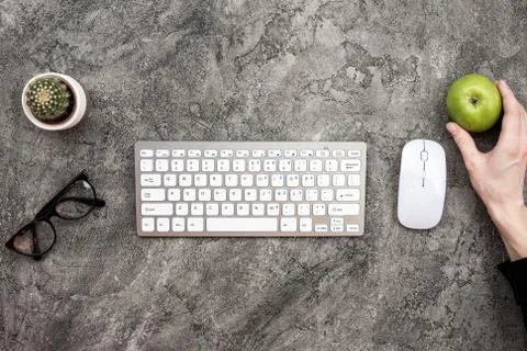 Top view keyboard, glasses, mouse and a fresh green apple in male hand Stock Photos