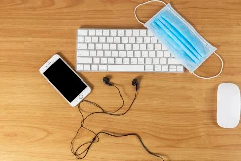 Top view keyboard, mouse, smartphone, headphone and face mask on wood table w Stock Photos