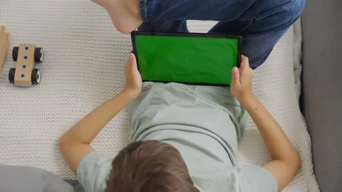 Top view kid tilting to the left and right a tablet, green screen. Chroma key Stock Footage 255510921