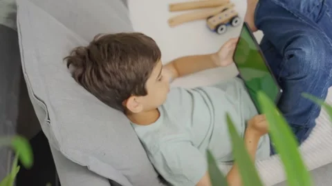 Top view kid tilting to the left and right a tablet, green screen. Chroma key Stock Footage 255511558