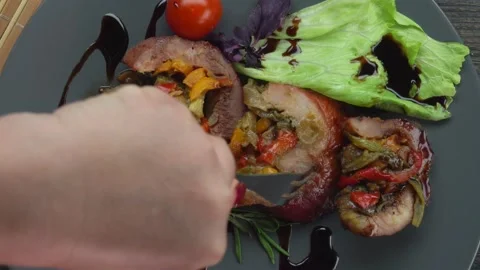 Top view of a knife that cuts a piece from a meat roll with vegetables Stock Footage 232954940