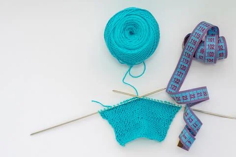 Top view of a knitted pattern on a knitting needle made of blue yarn, a centi 库存照片