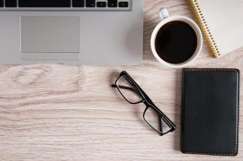 Top view of laptop and notepad with glasses and pocketbook on wood desktop an Stock Photos