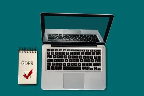 Top view of a laptop and a notepad with GDPR and a ticked checkbox on it, with Stock Photos