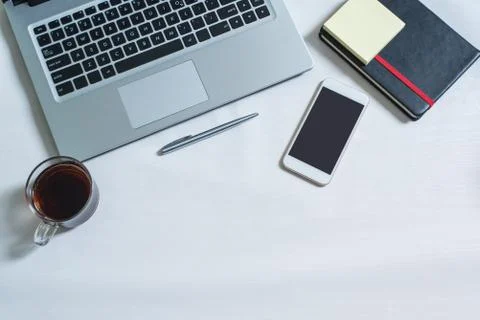 Top view of laptop, black notebook, cellphone, pen, a cup of tea Stock Photos