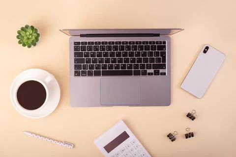 Top view laptop computer, calculator, cup of coffee and smartphone on beige.. Stock Photos