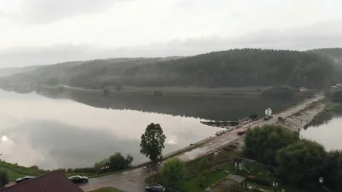 Top view of a large river with a forest on the bank in fog and a road with a dam 库存影片 152386318