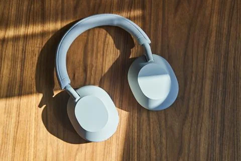 Top view of large white wireless headphones lying on a wooden table Stock Photos