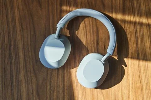 Top view of large white wireless headphones lying on a wooden table Stock Photos
