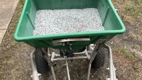 Top view of a lawn fertilizer spreader cart filled with mineral granules Stock Footage 342087460