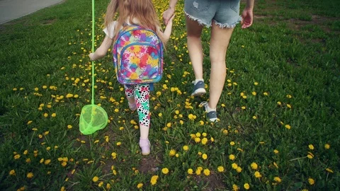 Top view of legs of child and young woman walking on yellow dandelions. Stock Footage 107901808