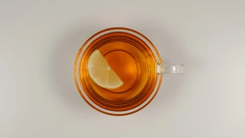 TOP VIEW: Lemon slice swims in a black tea in a glass tea cup on a table Vídeo Stock 92830764