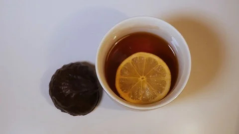 TOP VIEW: Lemon slice swims in a black tea in a glass tea cup on a table Video stock 118597514
