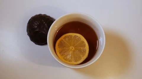 TOP VIEW: Lemon slice swims in a black tea in a glass tea cup on a table Stock Footage 119426308
