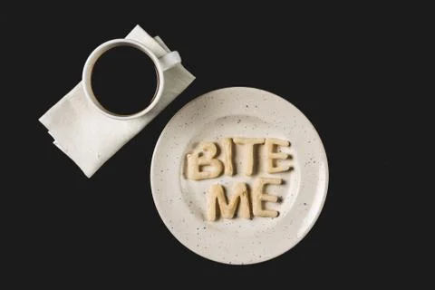 Top view of lettering bite me made from cookie dough on plate with coffee cup Foto stock