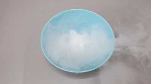 Top view of liquid nitrogen dry ice smoke bubbling in blue bowl on neutral .. Stock Footage 333822640