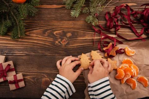 Top view of little kid seating at the table and holding Christmas cookies in  Stock Photos