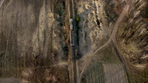 Top view of A locomotive and two carriages move along a narrow gauge railway Stock Footage 252575679
