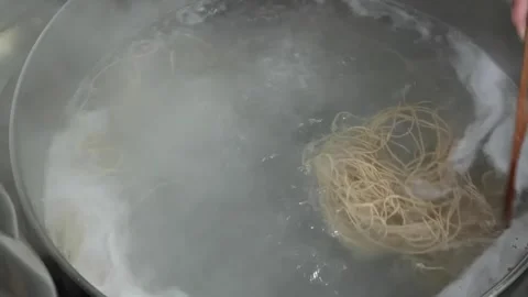 Top view of long thin noodles or spaghetti boiling in a large stainless steel po Stock Footage 333523803