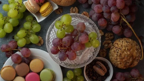 Top view loop of macarons on glass plate with red and green grapes buns bea.. Video stock 319967385