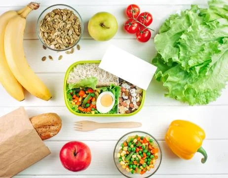 Top view of lunch box with empty card on white wooden background Stock Photos