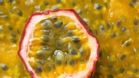 Top view macro of halved passion fruit rotating over juicy pulp background Stock Footage 344288618
