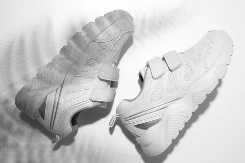 Top view macro two white sneakers with hard summer sun shadows from a palm tr Stock Photos