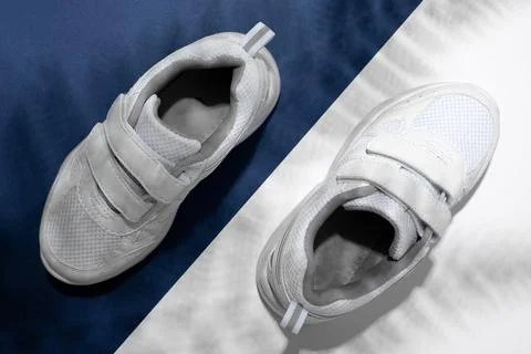 Top view macro two white sneakers with hard summer sun shades of palm or fern Stock Photos