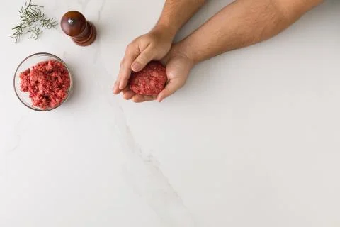 Top view of male hand molding a hamburger in a marble table, a glass bowl wit Stock Photos