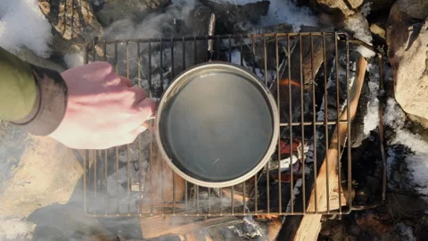 Top view of male hand puts boiler with water over bonfire at winter time Stock Footage 301363711