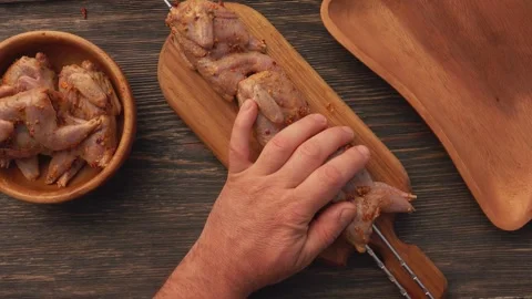 Top view of male hands piercing raw marinated quails with the skewers Stock Footage 278621048
