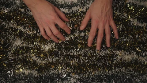 Top view of male hands preparing shiny tinsel garland with warm glowing lights Stock Footage 323348044