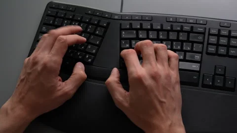 Top view of male hands typing on black ergonomic keyboard placed on gray office Stock Footage 342769526